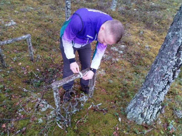 Kilpailunjohtaja valmistelee rastipistettä kierrätyshengessä Kilpailunjohtaja valmistelee rastipistettä kierrätyshengessä